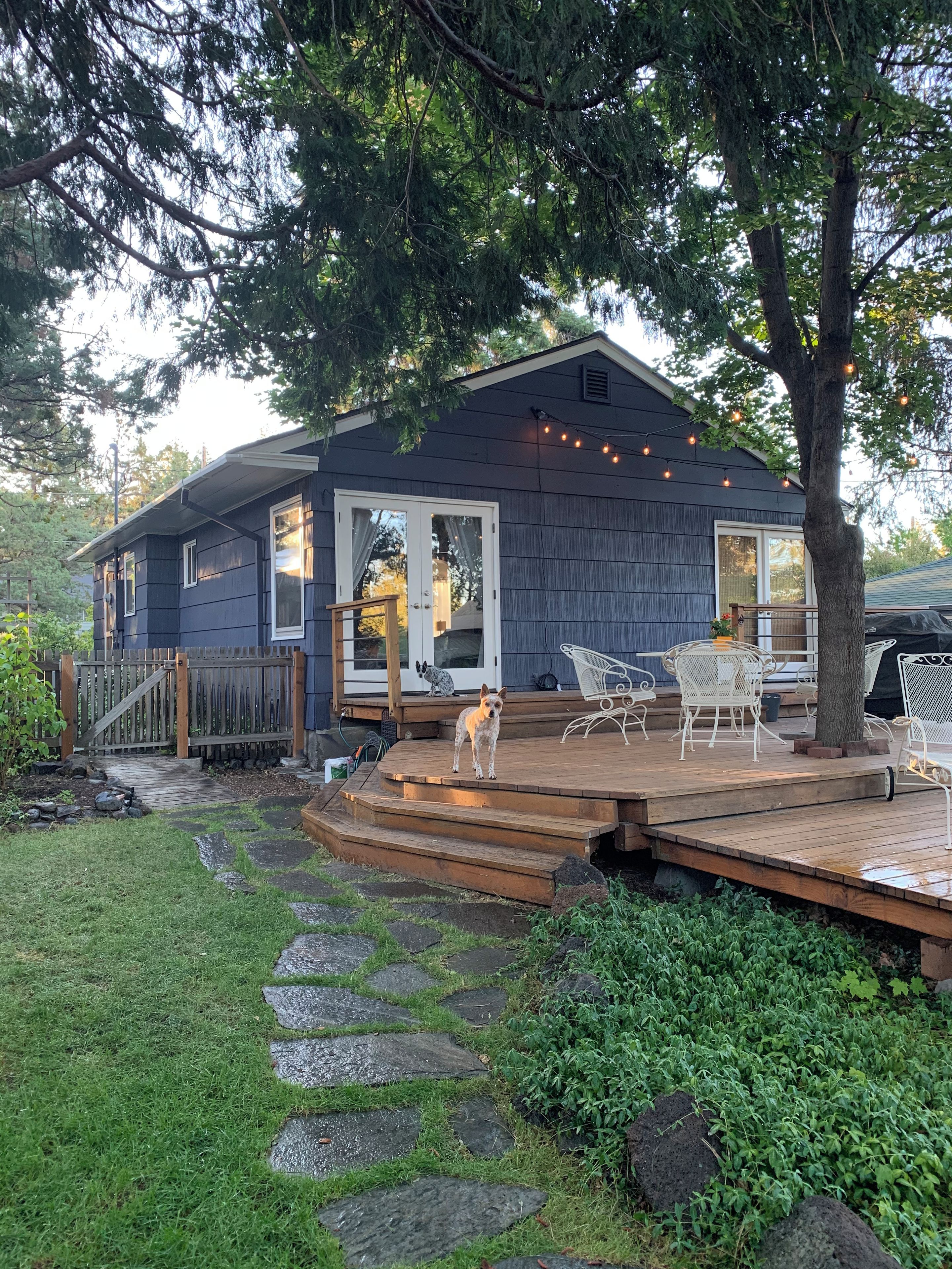 Una casa con terraza, mobiliario exterior y un perro.