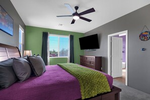 Ein Schlafzimmer mit Bett, Deckenventilator, Fernseher und Fenster.
