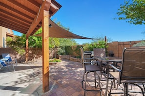 Eine Terrassenanlage im Freien mit einer Pergola, einem Grill und Sitzgelegenheiten.