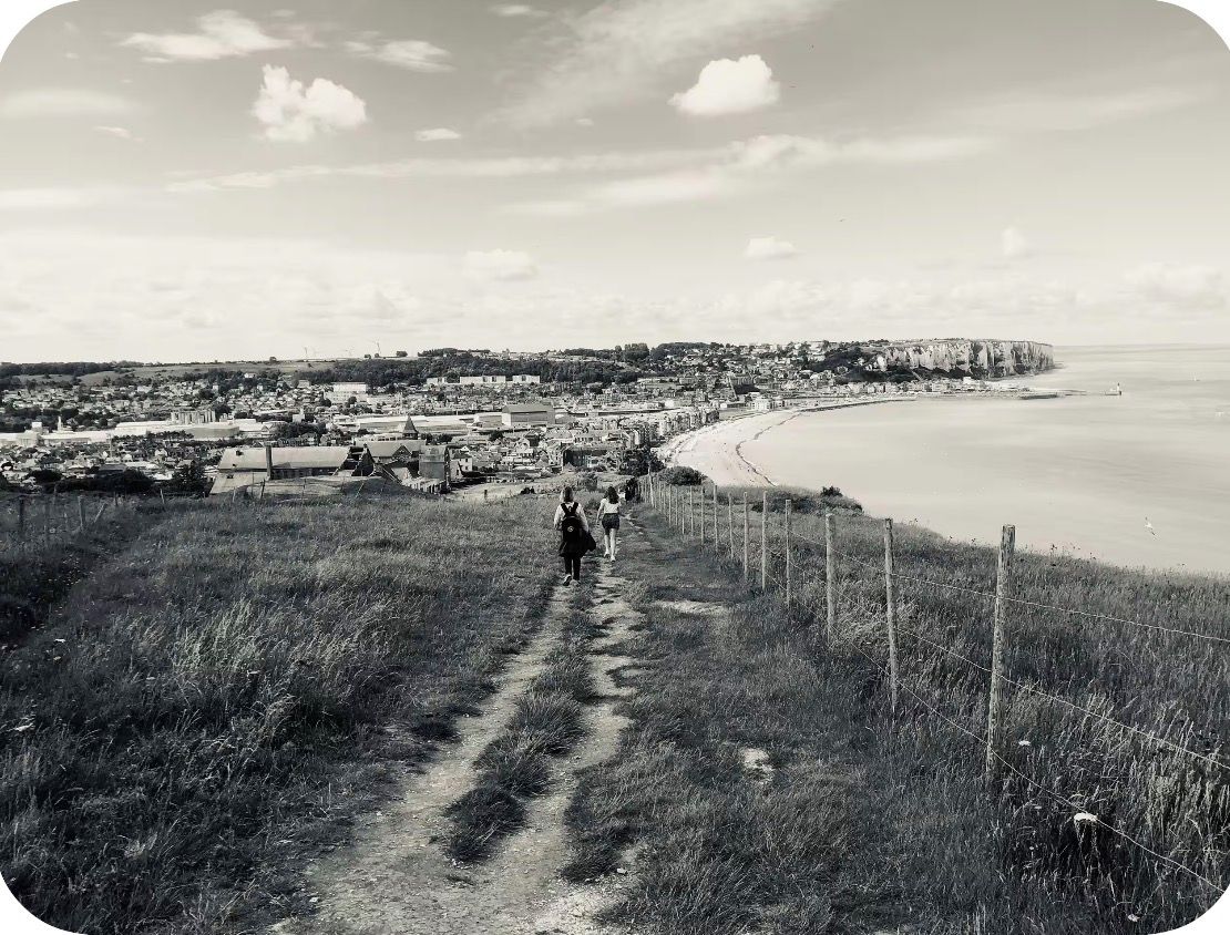 Eine Küstenstadt mit einem Weg zum Strand, Häusern und einer Klippe mit Blick aufs Meer.