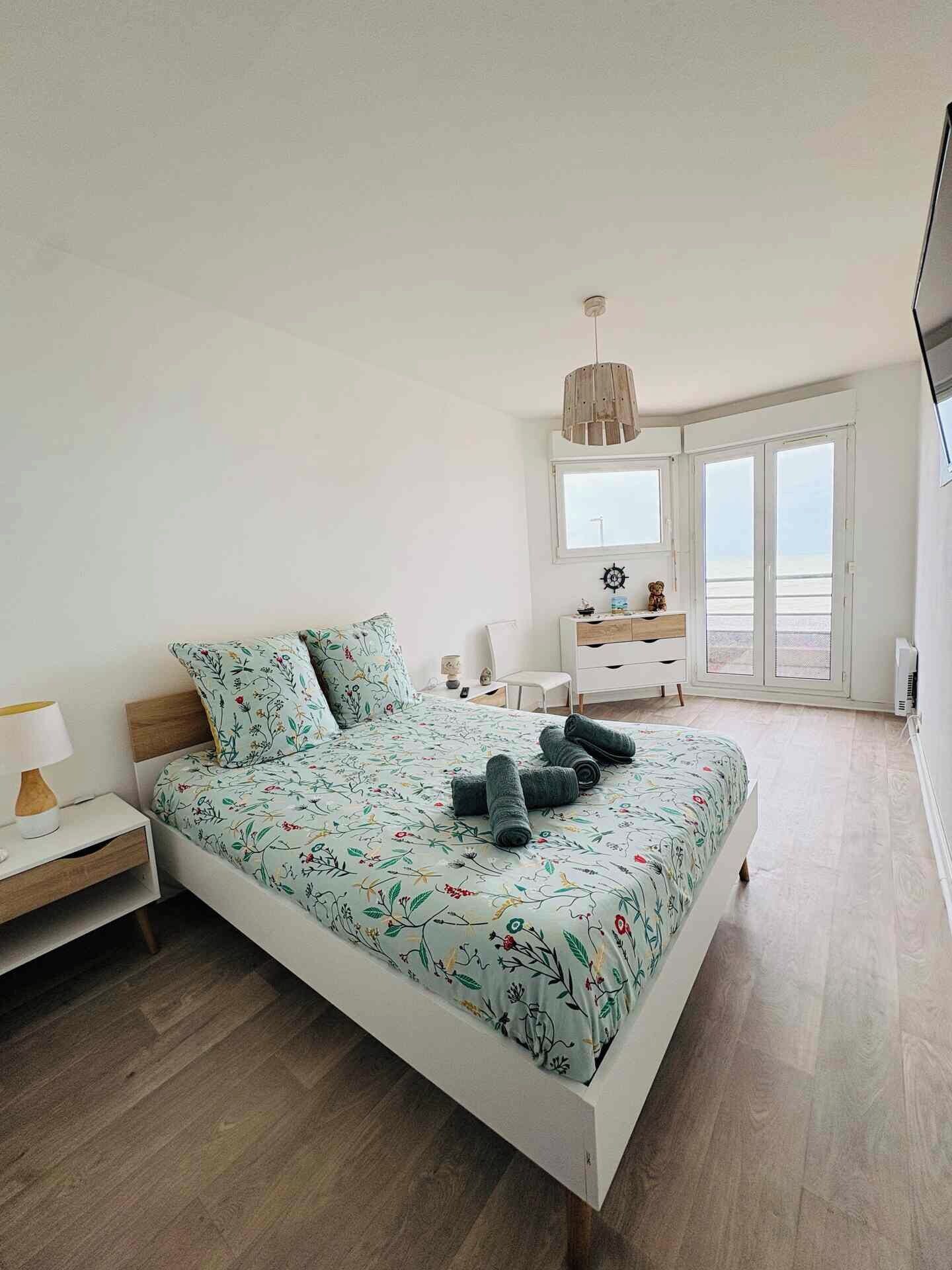 Une chambre à coucher comprenant un lit, une table de chevet, une commode et une fenêtre donnant sur un paysage agréable.