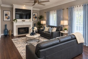 A living room with a fireplace, a sofa, a coffee table, and a TV. - Luxury Getaway Near Lake Lanier / Sleeps 10 (Buford)