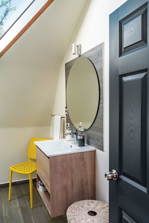 Un baño moderno con tocador de madera, un espejo grande y una silla amarilla.