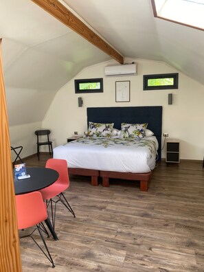 Un dormitorio con cama, una mesa y sillas, y un ventanal.
