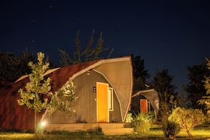 Una cabaña rústica con una sola puerta visible y una antena parabólica en el techo.