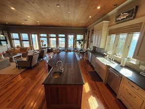 A spacious kitchen with a central island, wooden flooring, and large windows offering views of the ocean. - Waterfront Perdido Bay Home with Covered Boat Slip – Bring Your Boat! (Elberta)