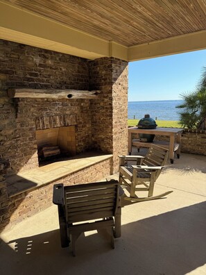 An outdoor patio with a brick fireplace, a grill, and seating. - Waterfront Perdido Bay Home with Covered Boat Slip – Bring Your Boat! (Elberta)
