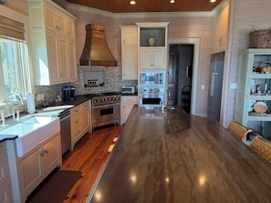 A modern kitchen with a central island, stainless steel appliances, and a brick backsplash. - Waterfront Perdido Bay Home with Covered Boat Slip – Bring Your Boat! (Elberta)