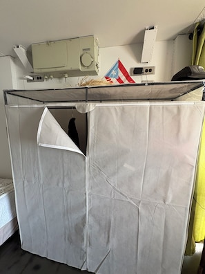Une pièce avec un lit, une fenêtre, un radiateur et un rideau.