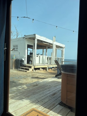 Une maison de plage avec une terrasse en bois, un jacuzzi et une vue sur l’océan.