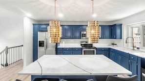 A modern kitchen with blue cabinets, stainless steel appliances, and a marble countertop. - Spacious 5-bedroom house in serene Kansas City (Kansas City)