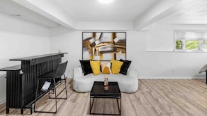 Un salon moderne avec un canapé blanc, une table basse noire et un grand tableau abstrait accroché au mur.
