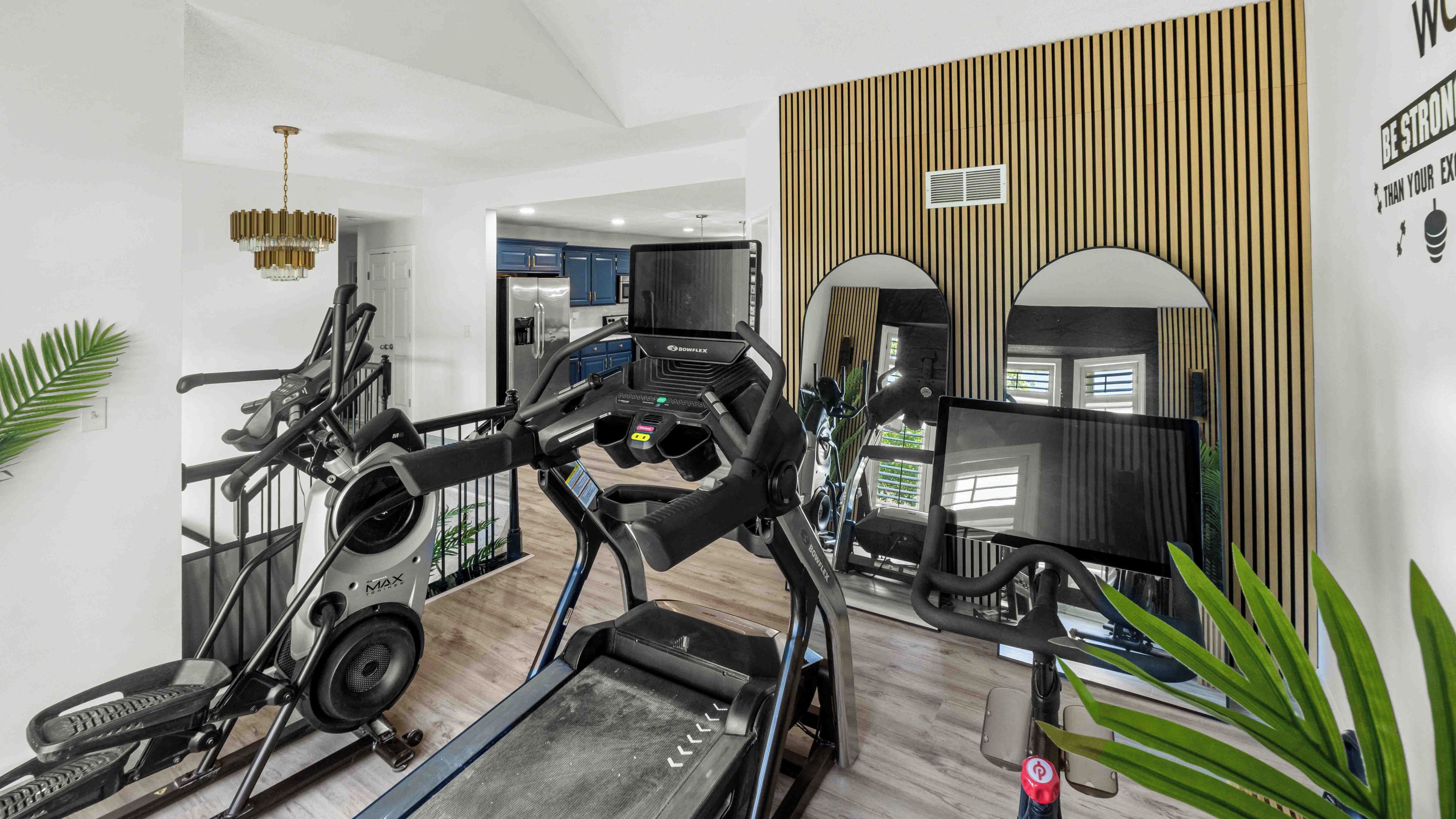 Une salle de sport à domicile équipée de tapis de course, d’un vélo d’appartement et d’un rameur.