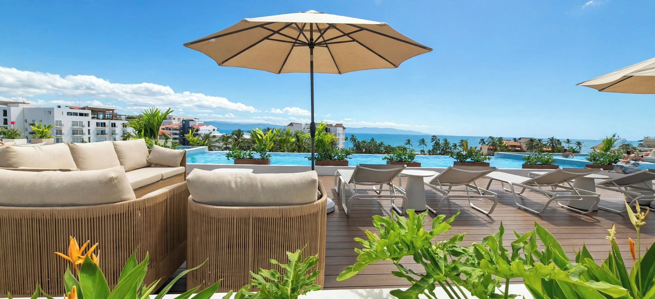 A poolside area with lounge chairs, a sofa, and an umbrella.
