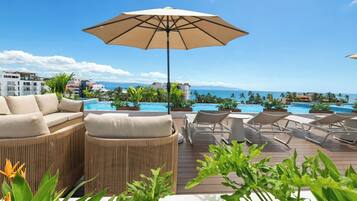 A poolside area with lounge chairs, a sofa, and an umbrella.