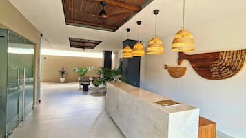 A modern reception area with a marble counter, hanging wicker lamps, and a large wall-mounted decorative piece.