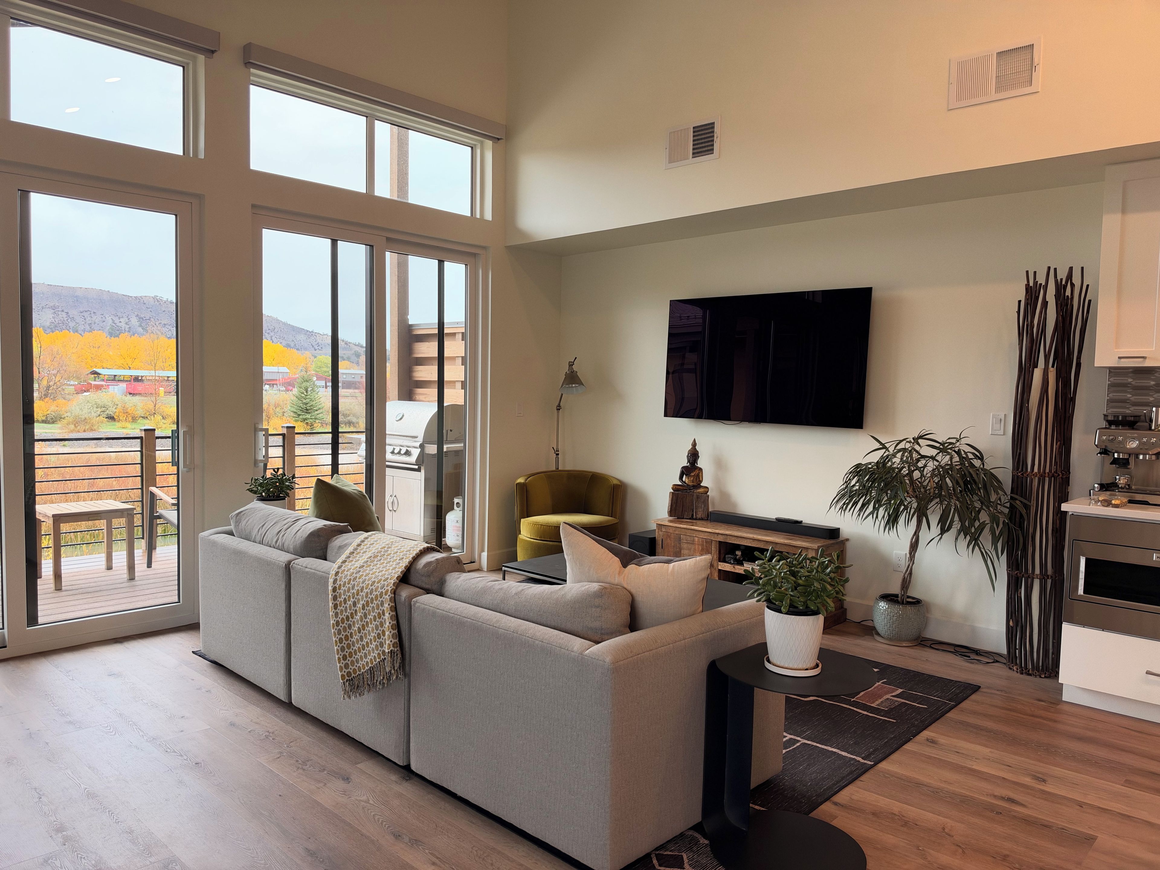 Una sala de estar moderna con un sofá, una televisión y un comedor con mesa y sillas.