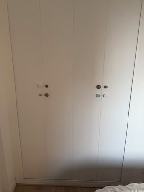 Een witte kast met twee deuren en een hendel in het midden.