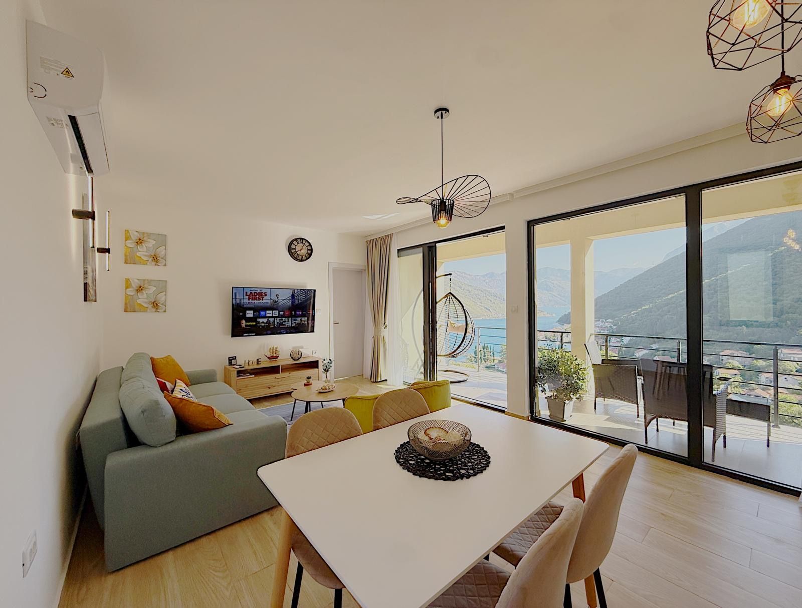 Una sala de estar moderna con un sofá, una mesa de comedor y un televisor montado en la pared.
