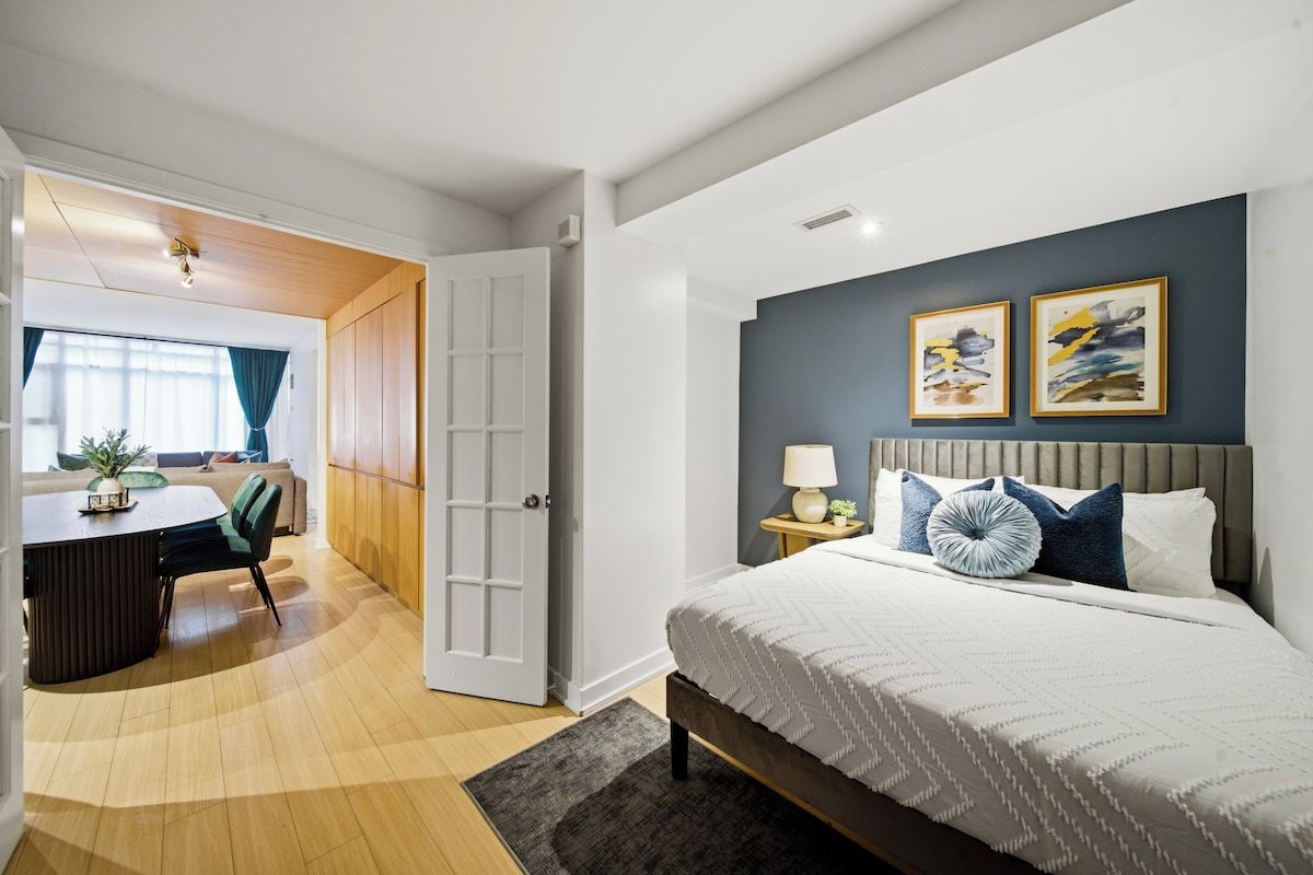 Une chambre à coucher moderne avec un lit, une table de chevet et une œuvre d’art accrochée au mur.
