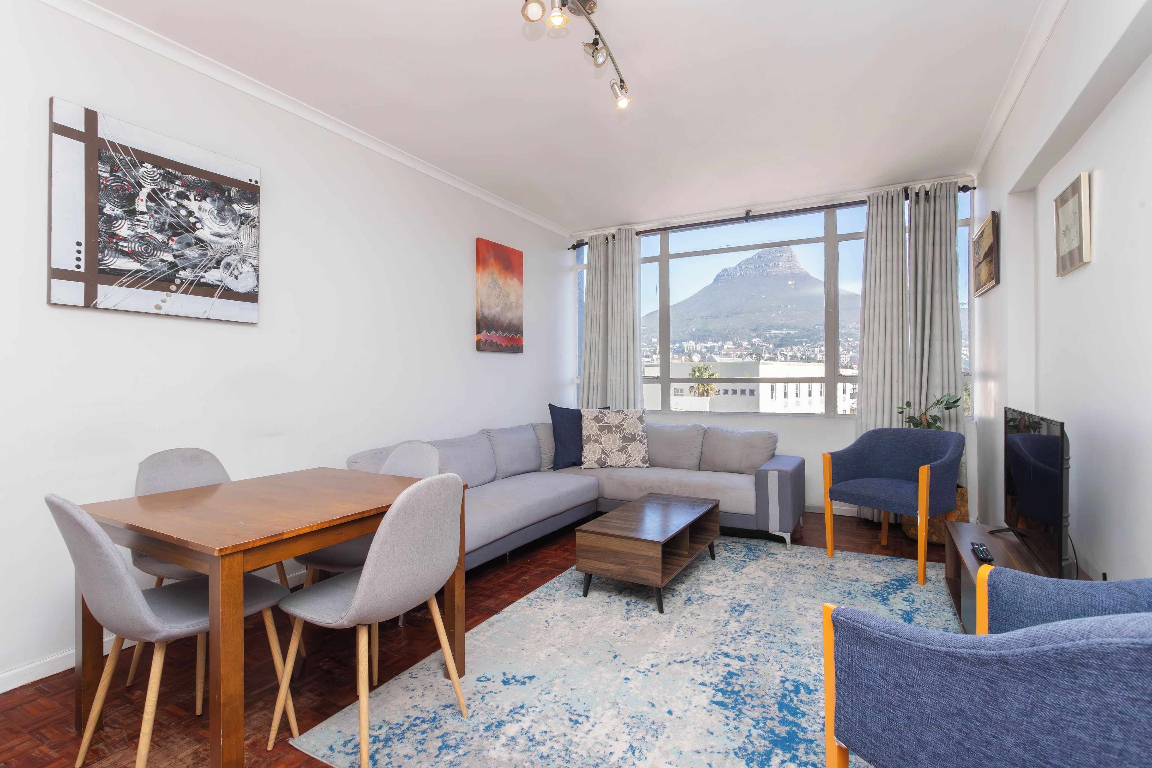 A modern living room with a dining area, a sofa set, a coffee table, and a TV.