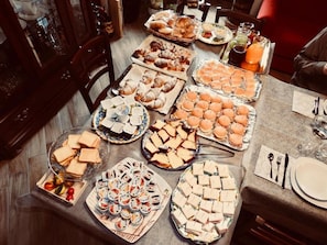 A buffet table with various food items and a dining area with chairs and a table set for a meal. - New Listing (Malvagna)