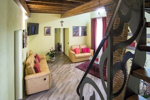 A living room with a sofa, a coffee table, and a rug. There is a staircase with a railing. - New Listing (Malvagna)