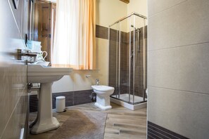 Ein modernes Badezimmer mit Waschbecken auf Säule, Toilette und einer Duschkabine.