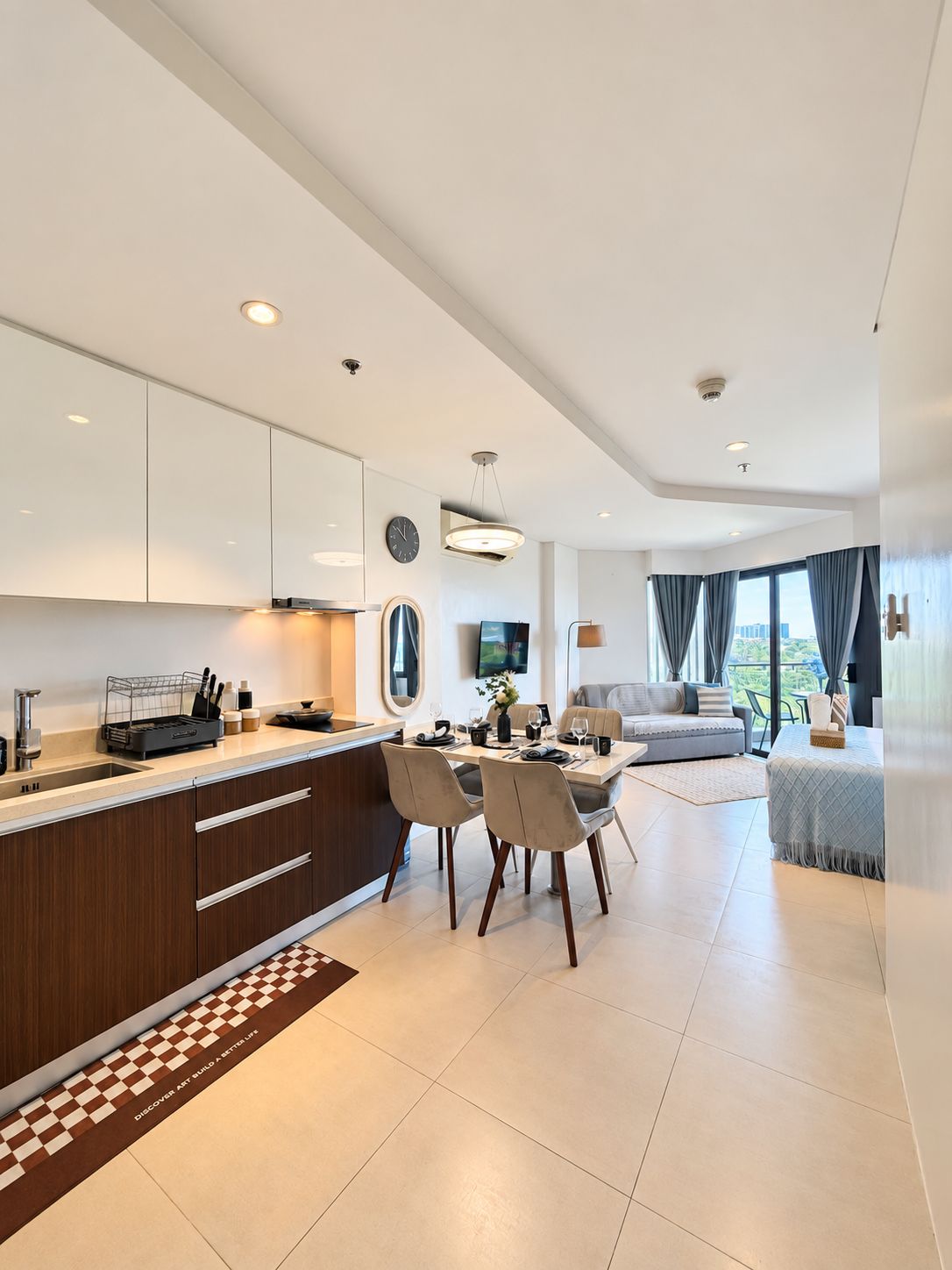 A modern kitchen with a dining area, a sofa, and a view of the outdoors.
