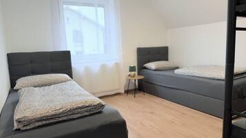 Ein Zimmer mit zwei Betten, einem kleinen Tisch und einem Fenster.