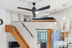 A compact living space with a loft bed, a staircase, a kitchenette, and a small bathroom. - Cute private cottage in Santa Paula with Views (Santa Paula)