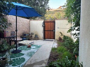 A patio area with a blue umbrella, a table with chairs, and potted plants. - Cute private cottage in Santa Paula with Views (Santa Paula)