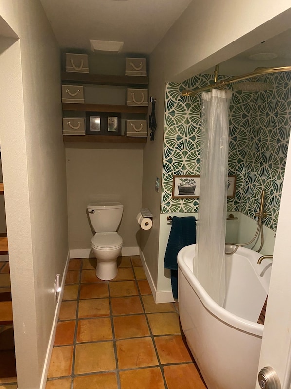 A bathroom with a toilet, a roll of toilet paper, a bathtub with a shower curtain, and a towel rack. - Cute private cottage in Santa Paula with Views (Santa Paula)