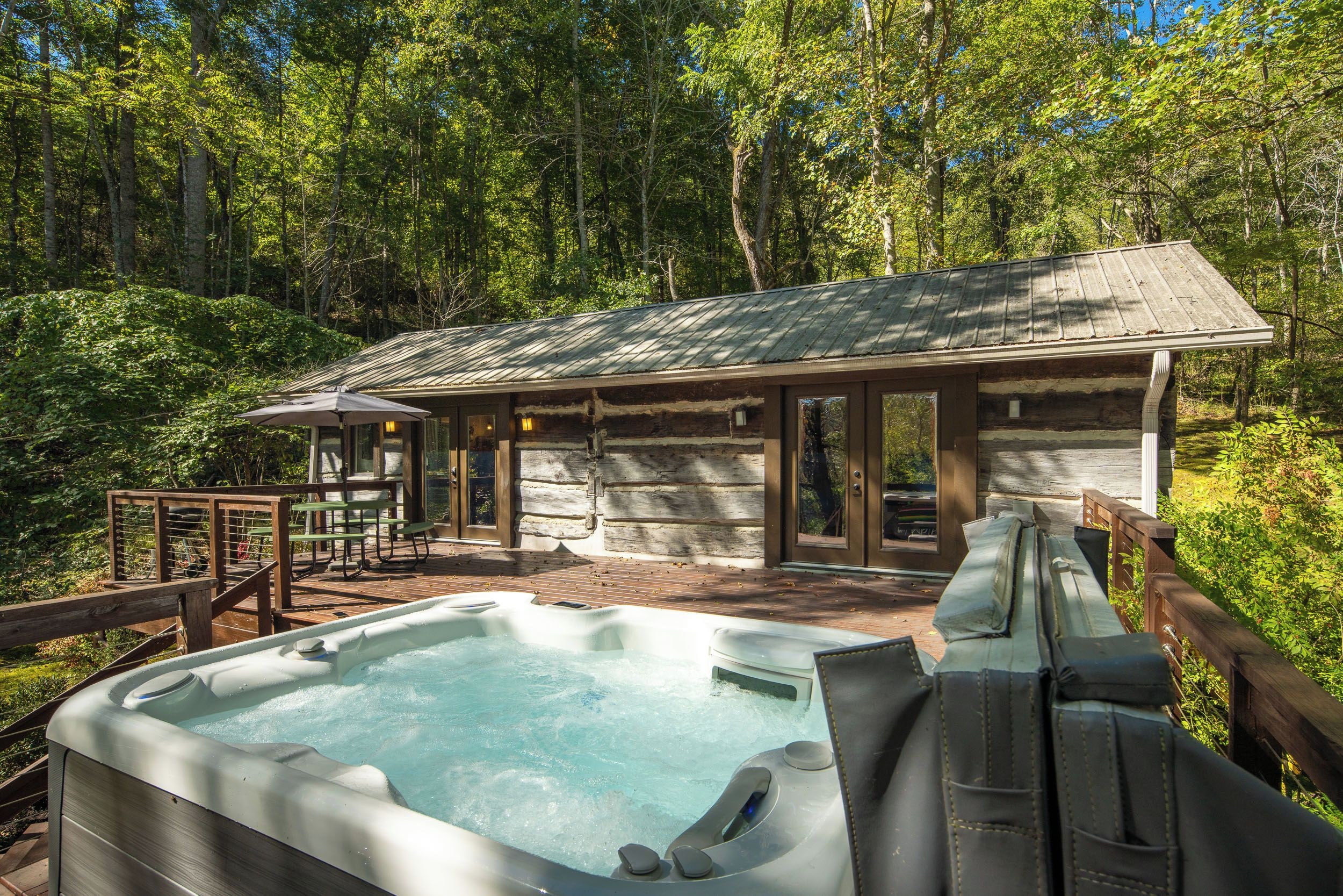 Een chalet met een hottub, een houten terras en picknicktafels.