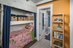 Ein Schlafzimmer mit einem Etagenbett, einem Bücherregal und einer Tür zu einem Badezimmer.