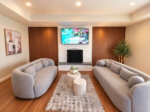 A modern living room with two grey sofas, a fireplace, a TV, and a decorative plant. - McHenry Riverfront Paradise -Relax, Gather & Make Memories! (McHenry)