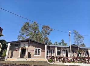 A two-story building with a brick facade, a covered entrance, and a fenced outdoor area. - Nature's Courtyard Resort (Dindori)
