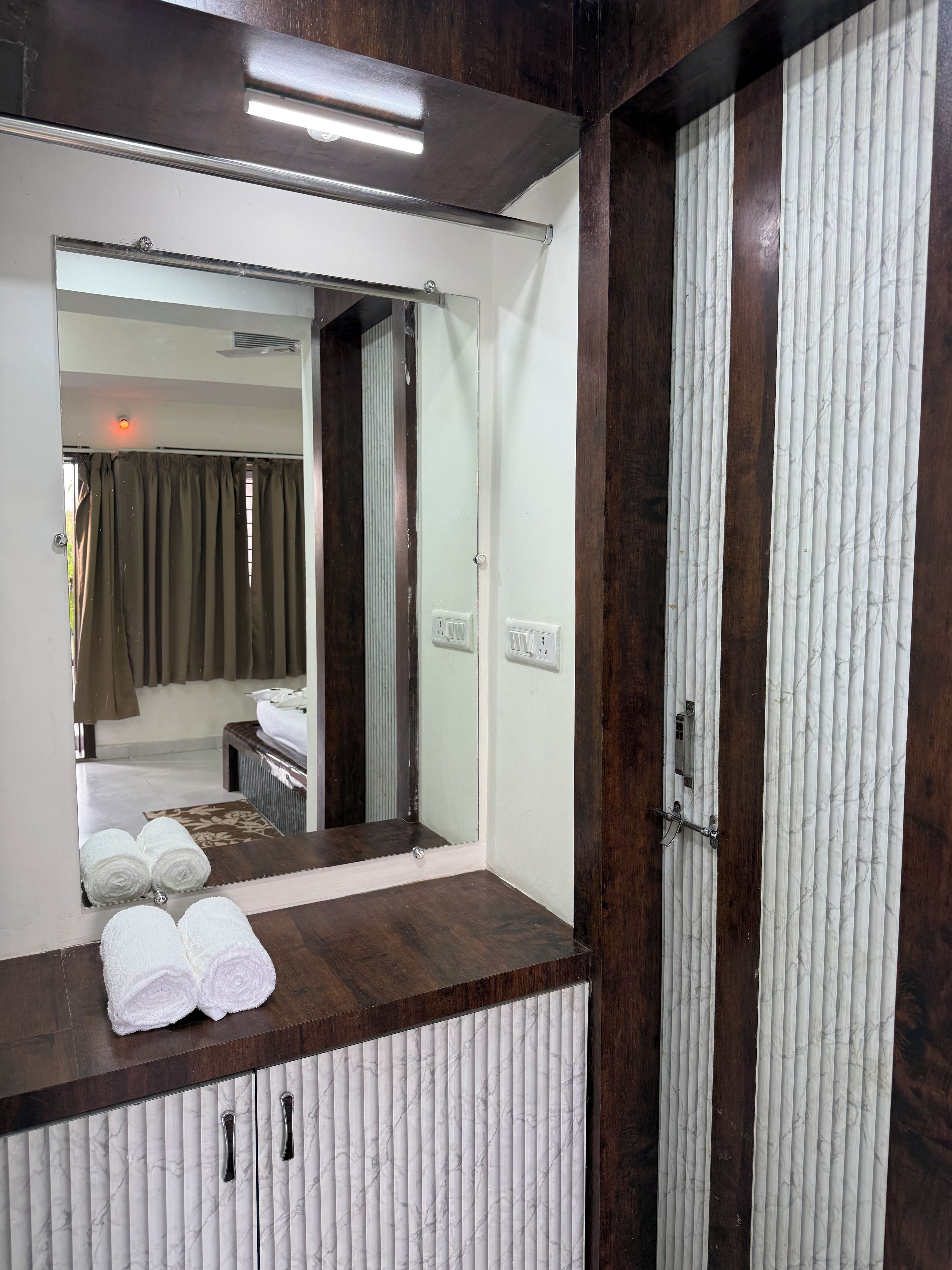 A bathroom with a mirror, wooden vanity, and a towel rack.