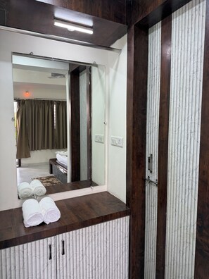 A bathroom with a mirror, wooden vanity, and a towel rack. - Nature's Courtyard Resort (Dindori)