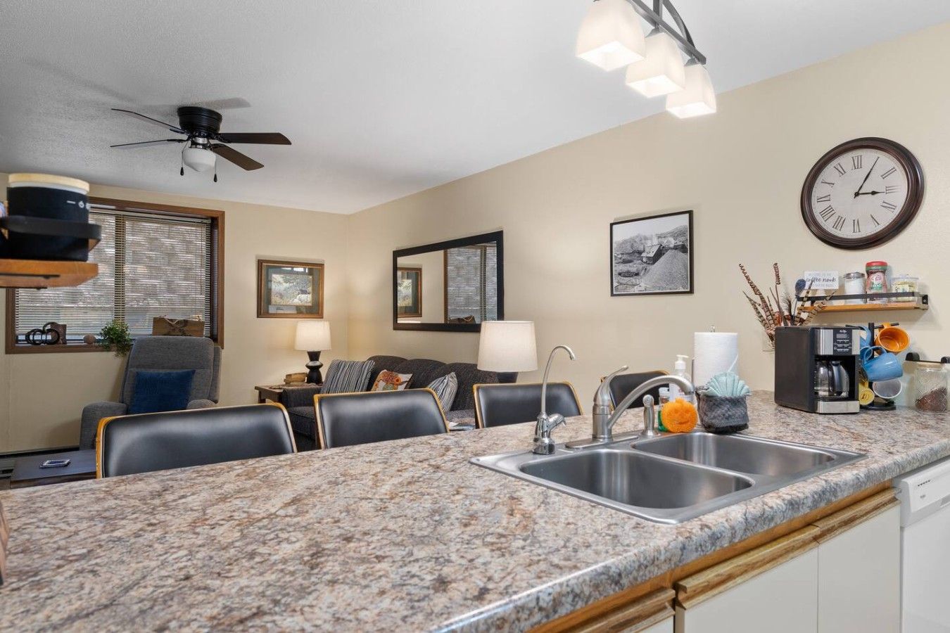 A modern kitchen with granite countertops, a built-in dishwasher, and a dining area with a sofa and chairs.