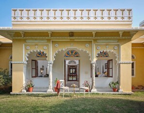 Ein traditionelles Gebäude mit einer gelben Fassade, verzierten Bögen und einem Balkon mit Geländern.