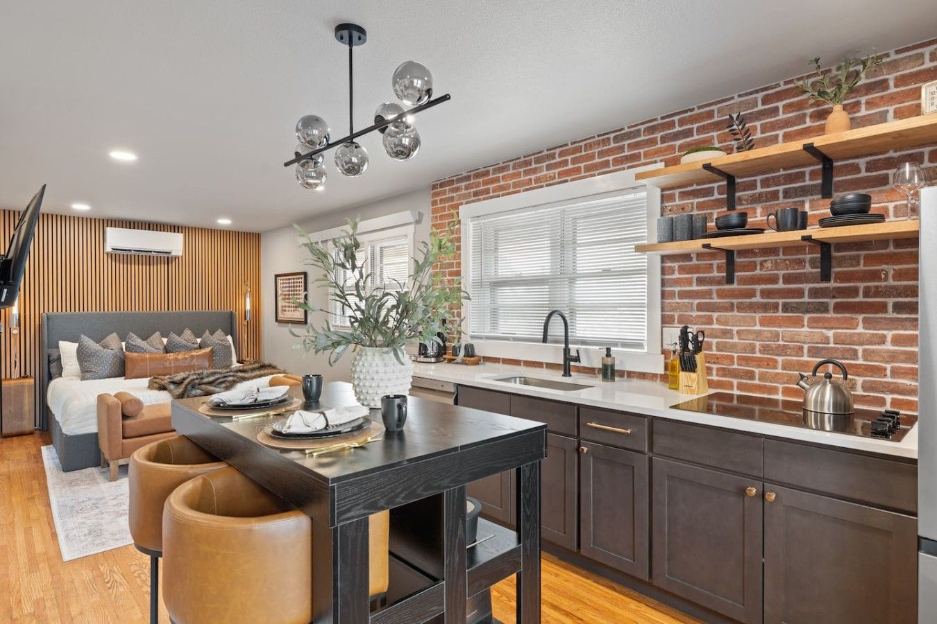 Una cocina moderna con pared de ladrillo, armarios de madera y un comedor con una mesa para dos.