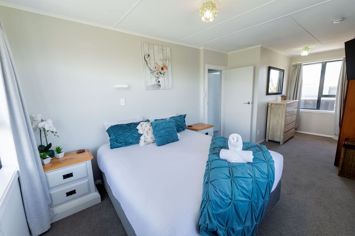 Une chambre d’hôtel avec un lit, une table de chevet, une commode et une fenêtre.