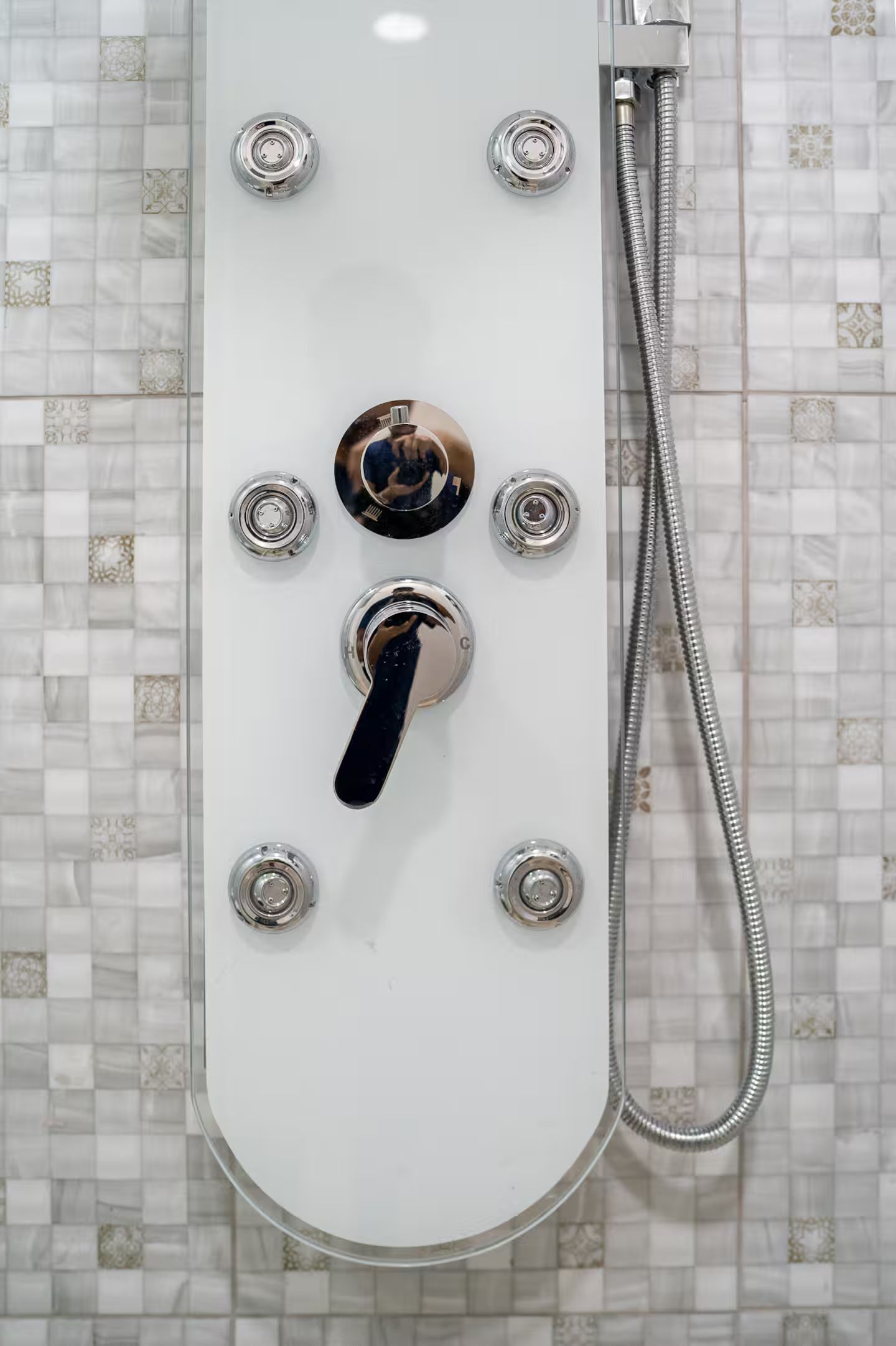 A white shower with a handheld showerhead and a flexible hose.
