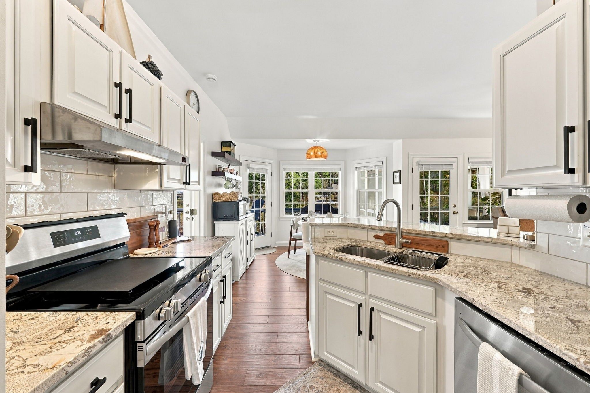A modern kitchen with white cabinetry, a stainless steel range, and a central island with a sink.