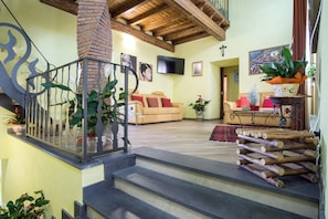 A spacious living area with a staircase, a sofa set, and a TV mounted on the wall. - New Listing (Malvagna)