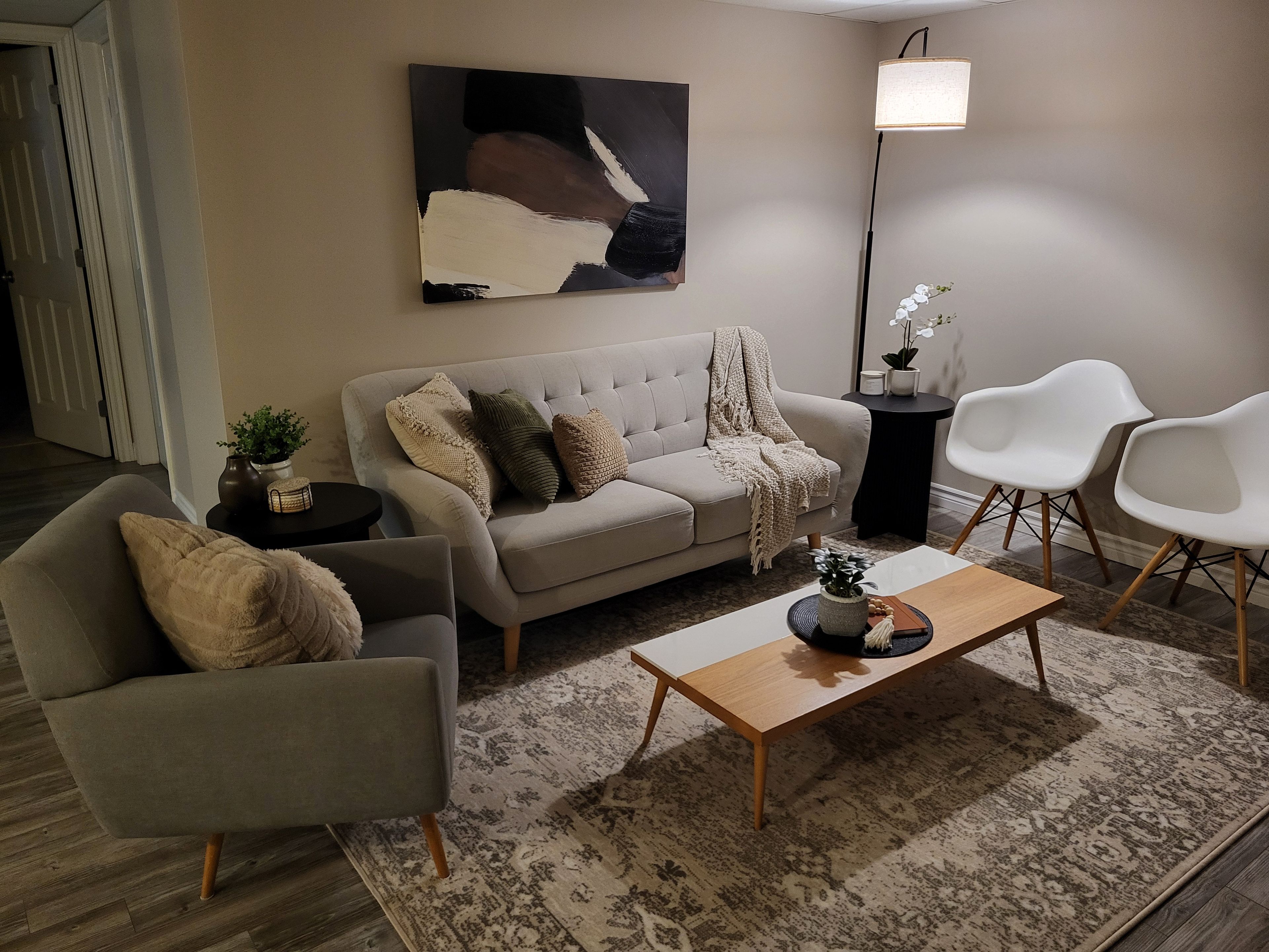 Un salon moderne avec un canapé, des fauteuils, une table basse et un lampadaire.