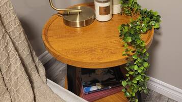 A round wooden side table with a brass lamp, a white candle, and a small potted plant.