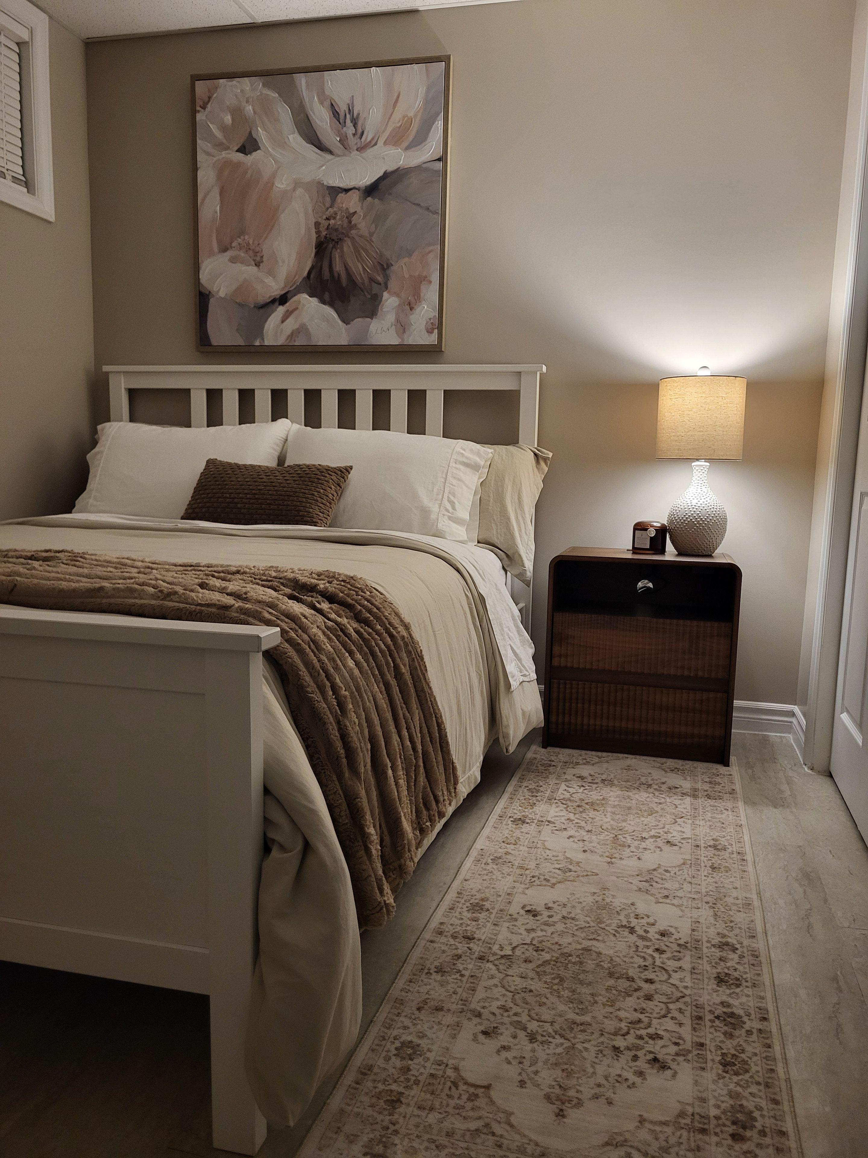 Une chambre à coucher avec un lit, une table de chevet, une lampe et un tableau au mur.
