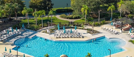 Zona de piscina en un resort con tumbonas, sombrillas y vistas despejadas del paisaje circundante.